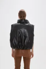 Chaleco puffer sin mangas confeccionado en cuero sintético negro, con cuello alto y cierre frontal.