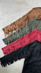 Chaqueta color beige de gamuza sintética con flecos en mangas y canesú, cuello camisero y cierre con botones.