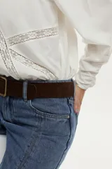 Blusa de algodón liviano color blanco, con detalles de puntilla en el frente, cuello mao con escote en V, cordón colgante y mangas largas abullonadas con puños ajustados.