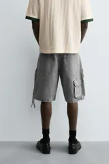 Bermuda de corte relajado en denim de algodón color beige, estilo cargo, con cinco bolsillos y bolsillos plastrón con solapa en las perneras.