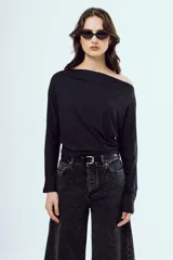 Top negro de manga larga, con escote asimétrico estilo off-shoulder y diseño drapeado.