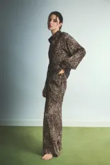 Pijama de dos piezas con estampado animal print de leopardo. Incluye una camisa de manga larga con cuello camisero y cierre frontal de botones, y un pantalón de corte recto y holgado con cintura elástica.