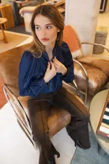 Camisa de denim azul con costuras a la vista en color contrastante, cuello camisero, mangas largas abullonadas con puños abotonados y corte holgado.