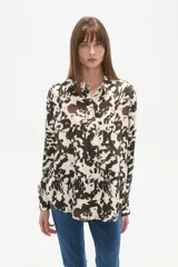 Camisa negra de viscosa con corte holgado, cuello clásico, cierre frontal de botones y detalle de tachas metálicas en la línea de los hombros.