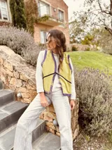 Chaleco color crema con ribete amarillo, de corte recto y sin mangas.