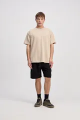 Remera de manga corta color beige con tejido texturado y pequeño logo impreso en el pecho.