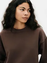 Buzo color crema de algodón, de corte holgado, con cuello redondo y mangas largas. Puños y ruedo acanalados.