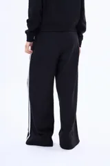 Pantalon de felpa color marrón con corte recto y holgado, presenta dos franjas blancas laterales a lo largo de cada pierna y cintura elástica.