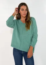 Sweater de punto color verde, con cuello en V, manga larga y diseño holgado con costura central vertical.