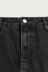Jeans de denim de algodón en color negro con efecto lavado, corte amplio y silueta curva tipo barrel fit con pinzas en las rodillas. Presenta diseño clásico de cinco bolsillos y cierre frontal con cremallera y botón metálico.