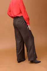 Pantalón sastrero de corte ancho y tiro alto, con diseño de líneas limpias, bolsillos laterales y cierre frontal con botón. Presenta una caída fluida y estructura amplia.