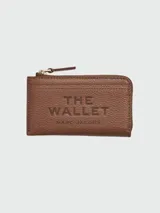 Billetera Marc Jacobs modelo The Top Zip Multi Wallet de cuero marrón texturizado, con cierre superior dorado, tarjetero exterior y el texto "THE WALLET MARC JACOBS" grabado en relieve al frente.