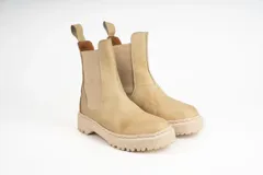 Bota tipo Chelsea de cuero negro con caña media, paneles laterales elásticos y suela track dentada.