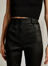 Pantalón de cuero negro, corte skinny, tiro alto, con cierre de botón y cremallera, bolsillos delanteros y acabado cosido.