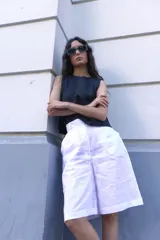 Bermuda blanca de lino, corte sastre, tiro alto, largo a la rodilla y bolsillos laterales.