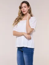 Blusa de corte holgado color marfil, confeccionada en mezcla de modal y algodón, con escote cuadrado y mangas cortas adornadas con detalles de puntilla calada.