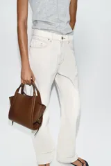 Bolso bandolera de formato city color marrón, con diseño estructurado, pespuntes decorativos, doble asa de mano y cremalleras laterales con tiradores colgantes.