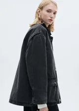 Chaqueta estilo vaquero de algodón en color negro lavado, con diseño oversize y acolchado interior. Presenta cuello camisero en contraste, cierre frontal con botones a presión, dos bolsillos de parche con solapa y dos bolsillos de ribete en la parte delantera.
