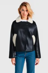 Campera corta negra de cuero sintético con cuello y bolsillos de piel sintética blanca, con cierre frontal con botones a presión.