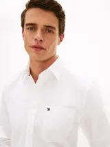 Camisa Tommy Hilfiger de corte regular, confeccionada en algodón Oxford elástico y ligero. Presenta cuello con botones, cierre frontal abotonado, mangas largas con puños redondeados y un bolsillo de parche en el pecho con el logo bordado.