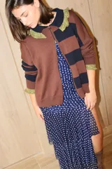Cardigan de tejido de punto con diseño a rayas horizontales en tonos marrón y azul marino. Presenta cierre frontal con doble cursor, cuello tipo polo con detalles en hilo metalizado dorado y puños con el mismo acabado brillante.