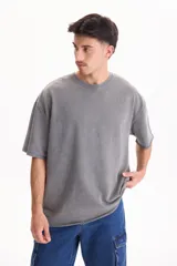 Remera oversize gris con efecto lavado, cuello redondo y mangas cortas.