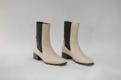 Botas de cuero color beige con elásticos laterales negros, taco cuadrado y punta cuadrada.