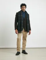 Bufanda de estilo escocés con diseño de cuadros en tonos verde, azul y líneas finas en rojo. Presenta flecos en los extremos y una etiqueta pequeña de la marca.