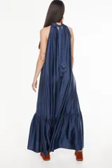 Vestido largo de viscosa color bordó, con cuello halter alto, corte holgado y volante fruncido en el bajo.