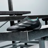 Championes Adidas Feroza Base Mer de color negro, con las icónicas tres tiras de la marca en tono plateado y detalles en color menta en el cuello y el lateral. Diseño aerodinámico de estilo deportivo.
