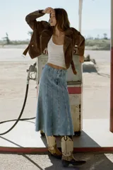 Falda midi de denim con diseño de paneles verticales marcados por costuras visibles. Presenta un corte evasé con bajo deshilachado y cierre frontal con cremallera, botón y gancho.