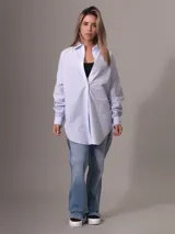 Camisa de algodón de corte oversized, color celeste con finas rayas verticales blancas. Presenta cuello clásico, cierre frontal de botones y dobladillo curvo.