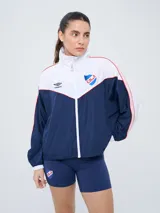 Campera deportiva Umbro del Club Nacional de Football, modelo Sky para mujer. Diseño en tonos azul marino y celeste con detalles en blanco y líneas finas rosadas, cuello alto, cierre frontal y bolsillos.