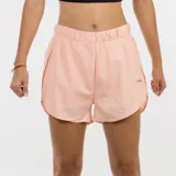 Short deportivo para mujer color salmón claro, con cintura elástica fruncida y aberturas laterales. Presenta un pequeño logo reflectante en la pierna derecha.