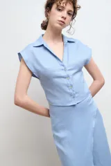 Camisa color beige claro de lino, con cuello clásico, abotonada al frente y sin mangas.