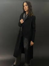 Tapado largo de paño de lana color negro con estampado abstracto brillante en el frente. Tiene cuello con solapas, bolsillos laterales y terminación al tallo vivo.