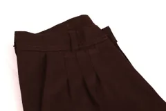 Pantalón de vestir azul marino, de corte recto, con bolsillos laterales y traseros. Se ajusta a la cintura con cinturón de cuero marrón. Tiene un cierre con botones en el tobillo.