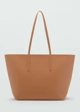 Bolso tipo shopper de tamaño grande, confeccionado en poliuretano con textura granulada. Cuenta con dos asas largas para llevar al hombro y cierre de cremallera en el compartimento principal.