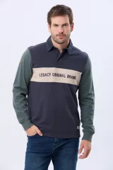 Remera tipo polo de manga larga con diseño color block en azul marino, verde y una franja central en beige con el texto Legacy Original Brand estampado. Presenta cuello camisero con cierre de botones y puños acanalados.