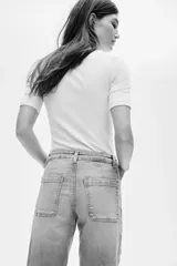 Jean de denim de algodón con tiro alto y pierna amplia de estilo wide leg. Presenta bolsillos tipo parche en la parte delantera y un lavado claro con efecto desgastado.