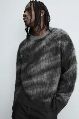Jersey de corte relajado con cuello redondo y manga larga, confeccionado en tejido cepillado con patrón jacquard en tonos oscuros y acabados en rib.