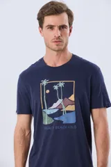 Remera azul marino de manga corta con cuello redondo y estampa frontal de un paisaje de playa con palmeras y el texto 'Legacy Beach Club'.