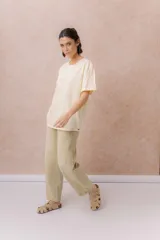 Jean de calce relajado y pierna amplia color beige, con tiro alto y detalle de recortes y costuras visibles.