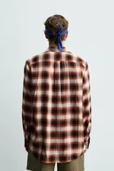 Camisa de corte regular fit confeccionada en tejido fluido de algodón y viscosa. Presenta un diseño de cuadros, cuello solapa, manga larga con puños abotonados, bolsillo en el pecho y cierre frontal con botones.