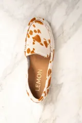 Mocasines de cuero con animal print de vaca en tonos blanco y marrón.