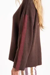Sweater de punto con cuello alto, diseño oversize y mangas largas. Presenta un contraste de color en el cuello y una franja vertical en las mangas en tono beige.
