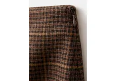 Falda midi de corte recto con diseño a cuadros en tonos marrones y negros, con una abertura frontal central.