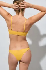 Top de bikini amarillo con textura sutil y detalle de aros metálicos entrelazados en el centro del escote, con tirantes finos.