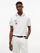 Chomba de corte regular confeccionada en algodón elástico, con cuello polo y cartera de dos botones. Presenta ribetes distintivos en cuello y puños, cinta lateral y múltiples logos bordados que incluyen Tommy Hilfiger, Cadillac Formula 1 Team y Pirelli.