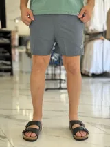 Short de baño gris liso, con diseño clásico y un pequeño parche circular con logo en la parte inferior de la pierna izquierda.
